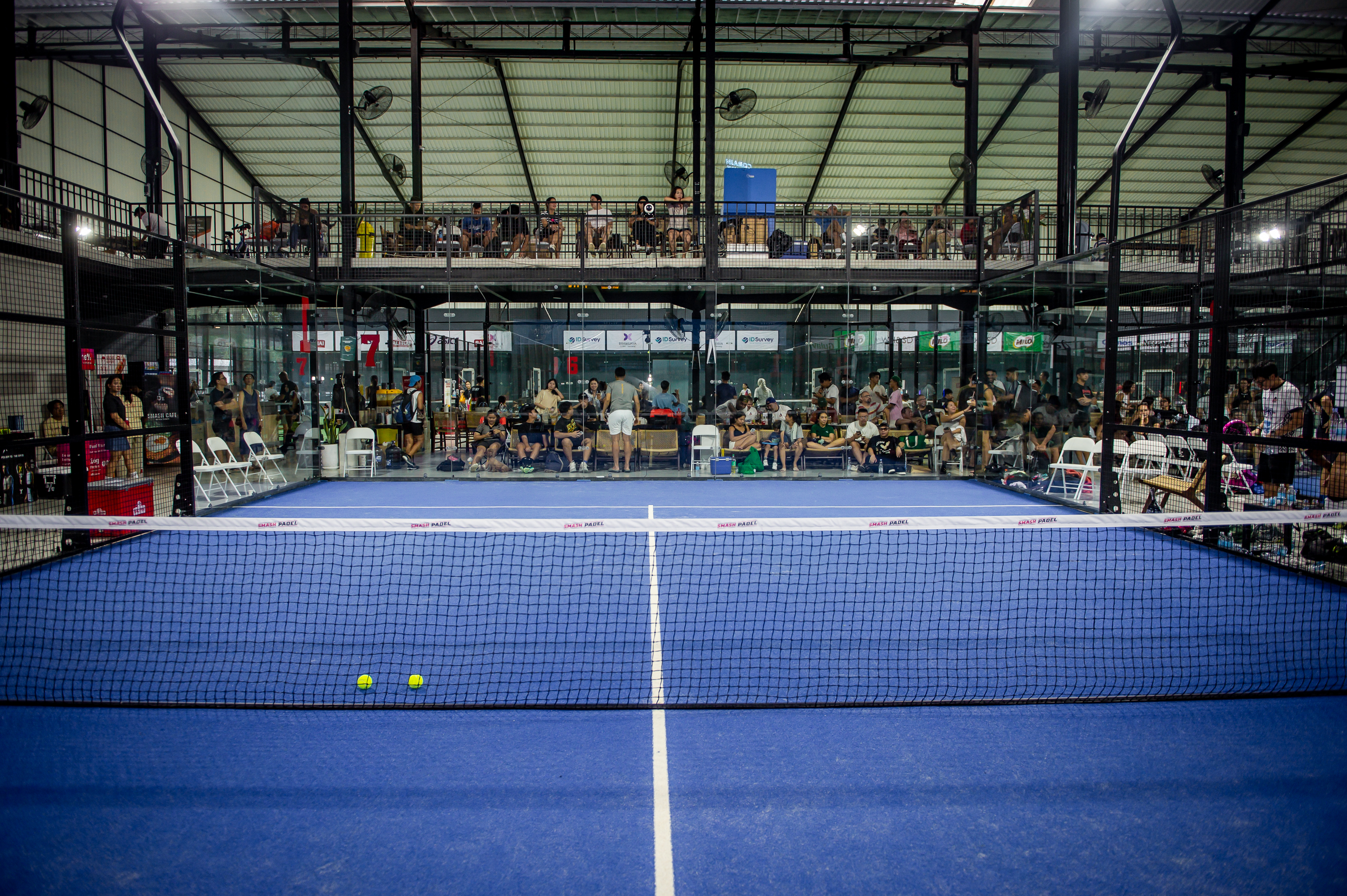 Busy match day atmosphere with crowd of players and spectators gathered on mezzanine level waiting for their turn