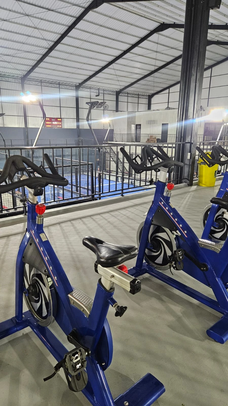 Second floor warm-up exercise bikes with panoramic view of padel courts below